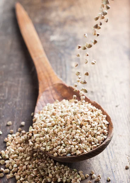 Versamento di grano saraceno verde in un cucchiaio di legno — Foto Stock