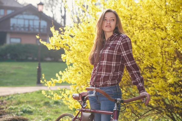Mooie jonge vrouw met vintage fiets in een park — Stockfoto