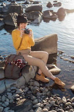 Genç kadın gezgin, doğanın fotoğraflarını geçmişe dönük kamerayla çekiyor.