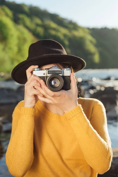 Young woman traveler is taking pictures of nature on retro camera — Stock Photo, Image