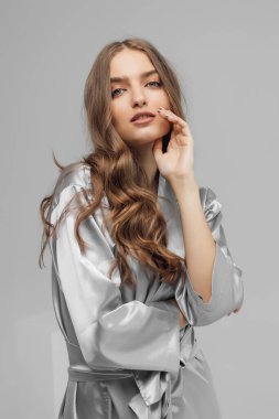 Beyaz arka planda saten bornozla estetik kadın portresi