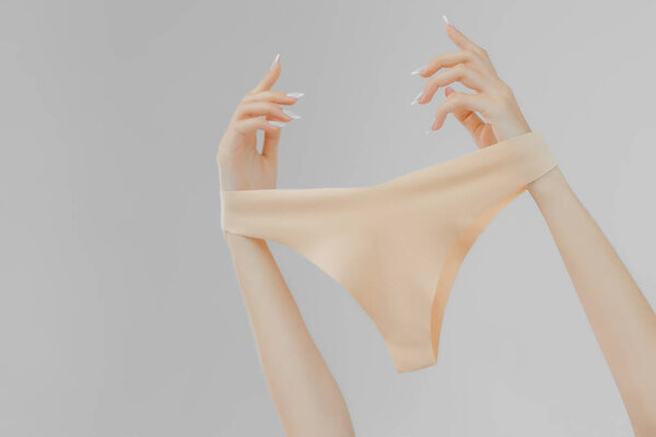 underwear in womans hands on white background