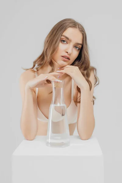 Elinde cam şişe su olan genç bir kadın. — Stok fotoğraf