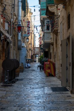 Malta, Valletta 'da dar bir cadde restoran ve barlarla dolu. Sokakta bir adam yürüyor, belki bir yerli ya da şehri gezen bir turist. Sokak ışıklarla süslenmiş..