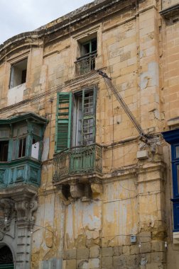 Malta 'daki yıpranmış cephe zamanın eskidiğini gösteriyor. Binanın balkonları ve taş duvarları eskimiş ama yine de mimarinin güzelliğini gösteriyor..