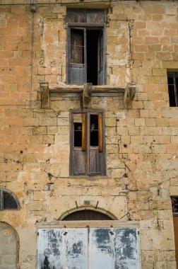 Eski bir binanın yıpranmış dış cephesi, içinde yaşlı taşlar, çürüyen pencereler ve güvercinler vardı. Binanın terk edildiği sırada onarılamayan ipuçları..