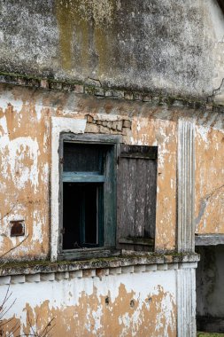 Terk edilmiş bir binanın çürüyen cephesi. Dökülen boya ve kırık cam ihmalkarlığı gösteriyor. Unutulmuş bir geçmişe ve zamanın tahribatına işaret ediyor..