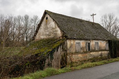 Terk edilmiş bir ev çürüyor, yıpranmış duvarları ve yosun kaplı çatısı ihmal hikâyesi anlatıyor. Doğa onu geri alır, zamanın geçişini hatırlatır..