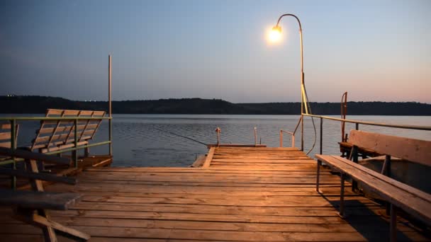 Träbrygga på sjön upplyst av lampa. — Stockvideo