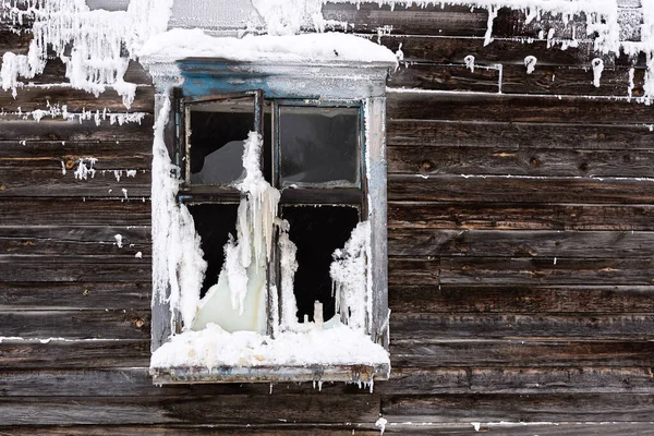 Frozen and broken window of an old wooden residential building close up