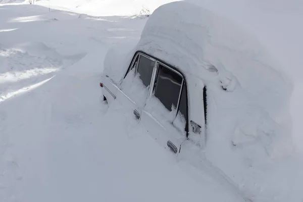 Snow covered passenger car on a winter road close up