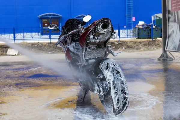 Washing a motorcycle with water and foam at a service station close up