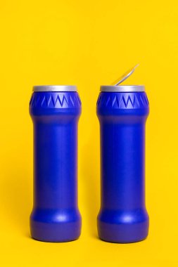 Sarı arka planda açık kapaklı iki şişe deterjan..