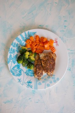 plate of grilled chicken with vegetables on background, top view.