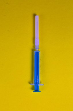 Sarı zemin üzerinde küçük turkuaz şırınga.