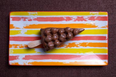 Çizgili tabakta sopa üzerinde fındıklı çikolatalı tatlı. en üstteki görünüm.