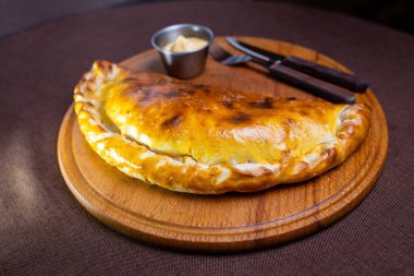 Yuvarlak bir tahtada balık ve soslu taze turta..