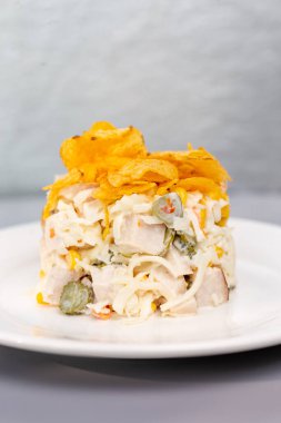 Tavuklu salata, salatalık ve beyaz tabakta cips..