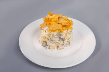 Tavuklu salata, salatalık ve beyaz tabakta cips..