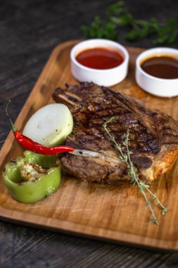 Ahşap bir arka planda soslu biftek ve otlar.