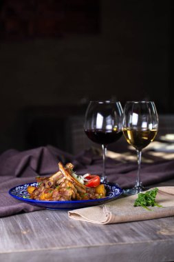 Kuzu kaburgası, soğanlı ve sebzeli ve masada şarap..