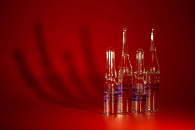 Kırmızı arka planda virüse karşı aşı şişeleri.