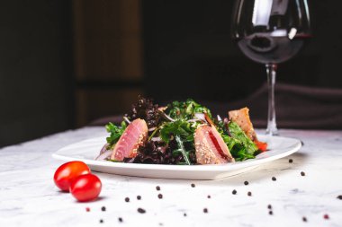 Beyaz tabakta yeşil sebzeli balık salatası..