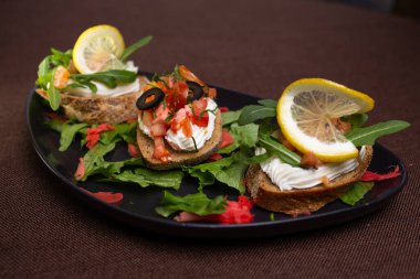 Krem peynirli, siyah tabakta zeytinli.