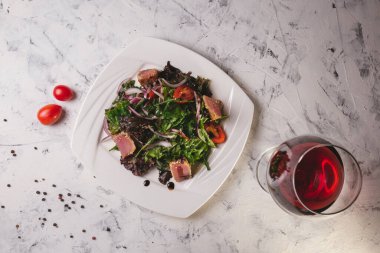 Beyaz tabakta yeşil sebzeli balık salatası..