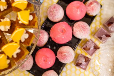 Açık büfedeki siyah tabakta pembe karamelli elmalar.