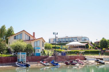 Sahildeki iskelede tatil köyünün arka planında mavi su vardı..