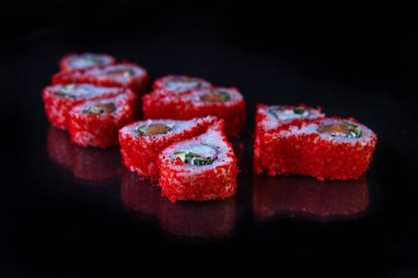 Japon mutfağı, siyah arka planda kırmızı havyarlı rulo..