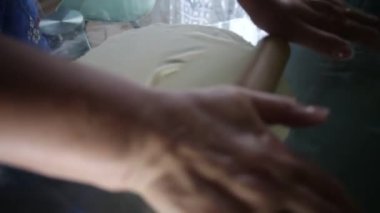 Bir kadın hamur işini masaya yuvarlar.