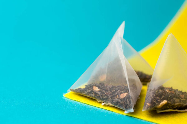 здоровый зеленый чай в мешке пирамиды на синем и желтом фоне.