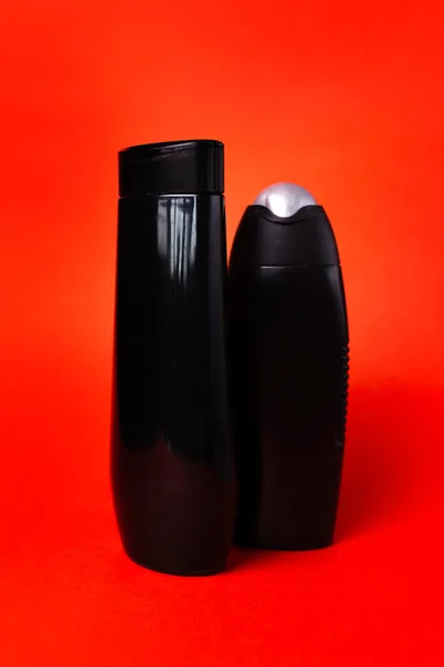 Due Bottiglie Plastica Nera Uno Sfondo Rosso — Foto Stock