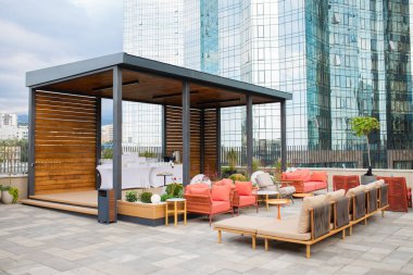 Oturma alanı olan modern çatı salonu, ahşap pavyon ve cam gökdelenlerden oluşan panoramik zemin. Otel, iş birliği ya da lüks emlak reklamları için mükemmel.