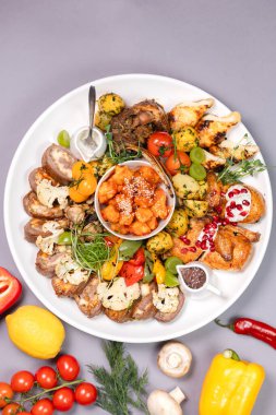 Overhead shot of stewed meat with diced potatoes, red pepper, and onions, served on a white oval plate against clean background.