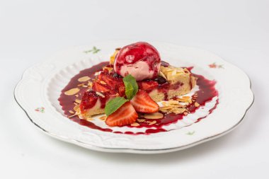 Dondurma kepçeli zarif çilekli tart, badem gevreği ve beyaz tabakta nane yaprakları, menüler ya da reklamlar için mükemmel..