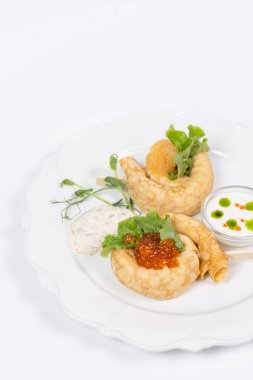 Kırmızı havyarlı zarif krepler ve beyaz tabakta yeşiller. Üst manzara - menüler, yemek fotoğrafçılığı ve reklamcılık için mükemmel.