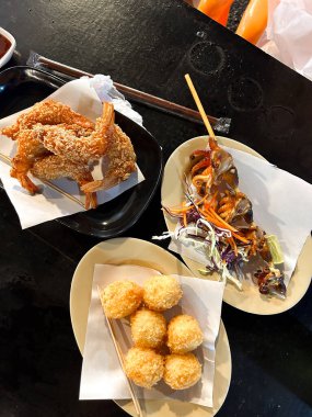 Çıtır karides, mısır topu ve tabakta ızgara ahtapot. Asyalı aperatifler siyah masada servis ediliyor. Yüksek kalite fotoğraf