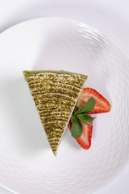 Çilekli ıspanaklı cheesecake dilimi ve beyaz arka planda nane şekeri.