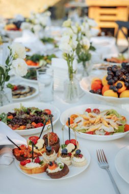 Bulanık çiçek masasına karşı keskin bir odak noktası olan hassas lokma büyüklüğünde aperatifler. Yemek servisi, düğün tasarımı ya da gurme yemek markası için mükemmel..