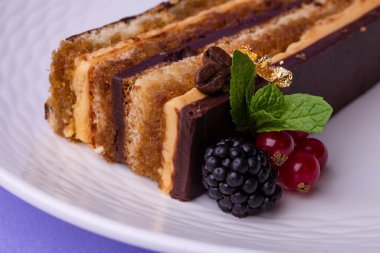 Katmanlı pasta, çikolata, karamel ve taze meyveli dokulu beyaz tabak..