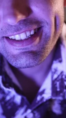 Adam mavi ışığın altında kameraya gülümsüyor..