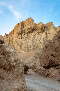 Eriyen kırmızı kaya oluşumları, büyük kayaların üzerinde belirgin bir şekilde yükselir ve Kazakistan 'ın Almaty yakınlarındaki Charyn Kanyonu' nun ikonik kaleler vadisinde tozlu bir patika oluşturur.