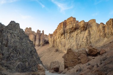Almaty yakınlarındaki Charyn Kanyonu 'ndaki dar Kaleler Vadisi' nin her iki tarafında yükselen dramatik kumtaşı uçurumları ve kabadayıların geniş görüşü berrak mavi gökyüzünün altında..