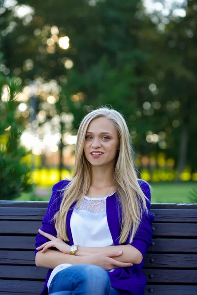 Portret pięknej blondynce w parku. Ona siedzi — Zdjęcie stockowe