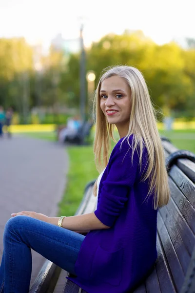 Porträt eines schönen blonden Mädchens im Park. sie sitzt — Stockfoto