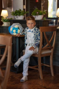 Çiçeklerle restoranda oturan sevimli küçük çocuk