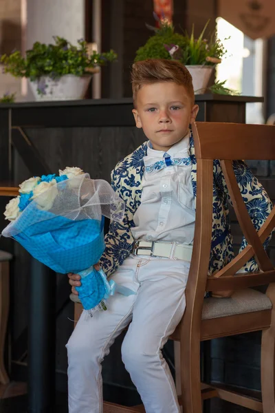 Çiçeklerle restoranda oturan sevimli küçük çocuk